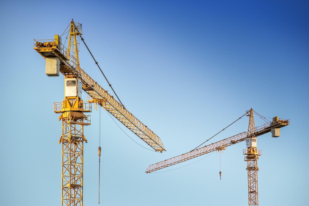 High-rise construction site with cranes and steel structure rising in a dense urban setting